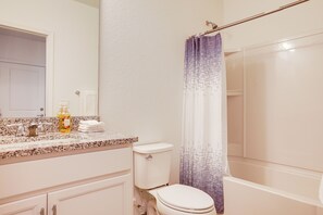Et badeværelse med toilet, håndvask og bruseområde.