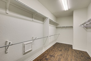 A room with white walls, wooden flooring, and multiple metal racks for hanging items. - Home Theater & Game Room! 7BR San Antonio Retreat (San Antonio)