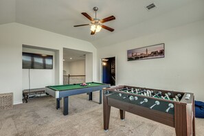 A room with a pool table, foosball table, and a ceiling fan. - Home Theater & Game Room! 7BR San Antonio Retreat (San Antonio)