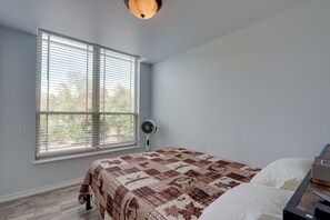A bedroom with a bed, a window with blinds, a standing fan, and a ceiling light. - 1/2 Mi to Lake Tenkiller Condo w/ Shared Game Room (Cookson)