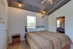 Une chambre à coucher comprenant un lit, une table de chevet, une fenêtre et une porte donnant sur une autre pièce.