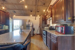 Une cuisine dotée de meubles en bois, de plans de travail en granit, d’appareils électroménagers en acier inoxydable et offrant une vue sur l’extérieur.