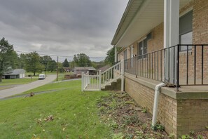 A residential building with a brick exterior, a white porch with a black railing, and a visible driveway. - Youngstown Home Near Fellows Gardens & Lake Milton (Youngstown)