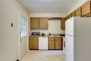 A kitchen with wooden cabinets, a microwave, a dishwasher, and a refrigerator. - Youngstown Home Near Fellows Gardens & Lake Milton (Youngstown)
