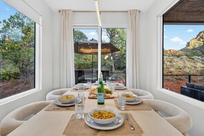 Un coin repas avec une table dressée pour six personnes, offrant une vue panoramique sur le paysage extérieur.