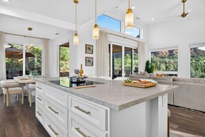 A modern kitchen with a large island, white cabinetry, and pendant lighting. - Covered Lounge + Fire Pit + BBQ | Red Rock Views + Mins to Town | Casa Alta (Sedona)