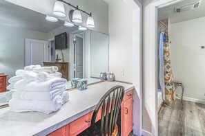 A bathroom with a large mirror, a sink with a countertop, and a stack of white towels. - Comfortable Cabin w/ Hot Tub, Near Old Midtown (Ruidoso)