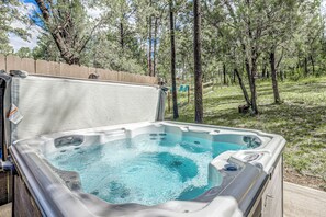 A hot tub with a wooden deck and a view of a forested area. - Comfortable Cabin w/ Hot Tub, Near Old Midtown (Ruidoso)