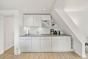 Una cocina moderna con armarios blancos, un lavamanos de acero inoxidable y un horno empotrado.