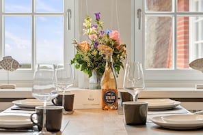 Ein Esstisch ist gedeckt, mit einer Champagnerflasche, Blumen in einer Vase und einer Speisekarte.