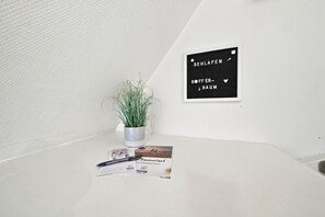 Ein heller Raum mit einem Blumentopf, einem gerahmten Schild und Büchern auf einem Tisch.