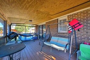 Eine überdachte Terrasse im Freien mit einer Hängematte, einer Bank und einem Tisch.