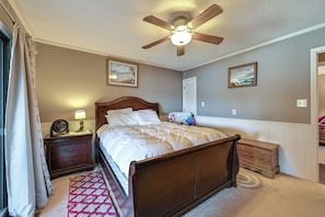 Ein Schlafzimmer mit einem hölzernen Bett, einem Nachttisch mit Lampe, einem Deckenventilator und zwei Wandbildern.