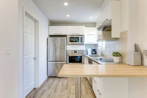 A modern kitchen with stainless steel appliances, a wooden countertop, and white cabinetry. - Extended Beach Escape: Santa Monica Studio! (Santa Monica)