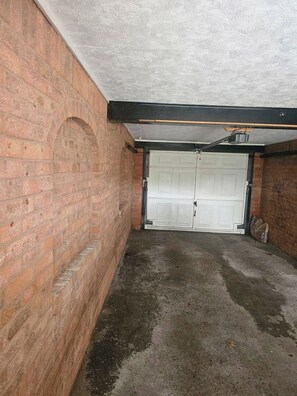 Eine Garage mit weißer Tür, Ziegelwänden und einem Betonboden.