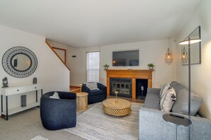 Ein Wohnzimmer mit Kamin, Sofas, einem Couchtisch und einem Fernseher.