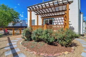 A covered porch with a wooden railing, a small window, and a garden area with shrubs and stepping stones. - Charming Mid-Term Retreat in Louisville Colorado (Louisville)