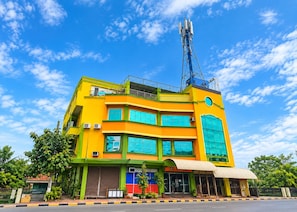 Um edifício com vários andares, uma antena imponente no telhado, amplas janelas e uma área de entrada coberta.