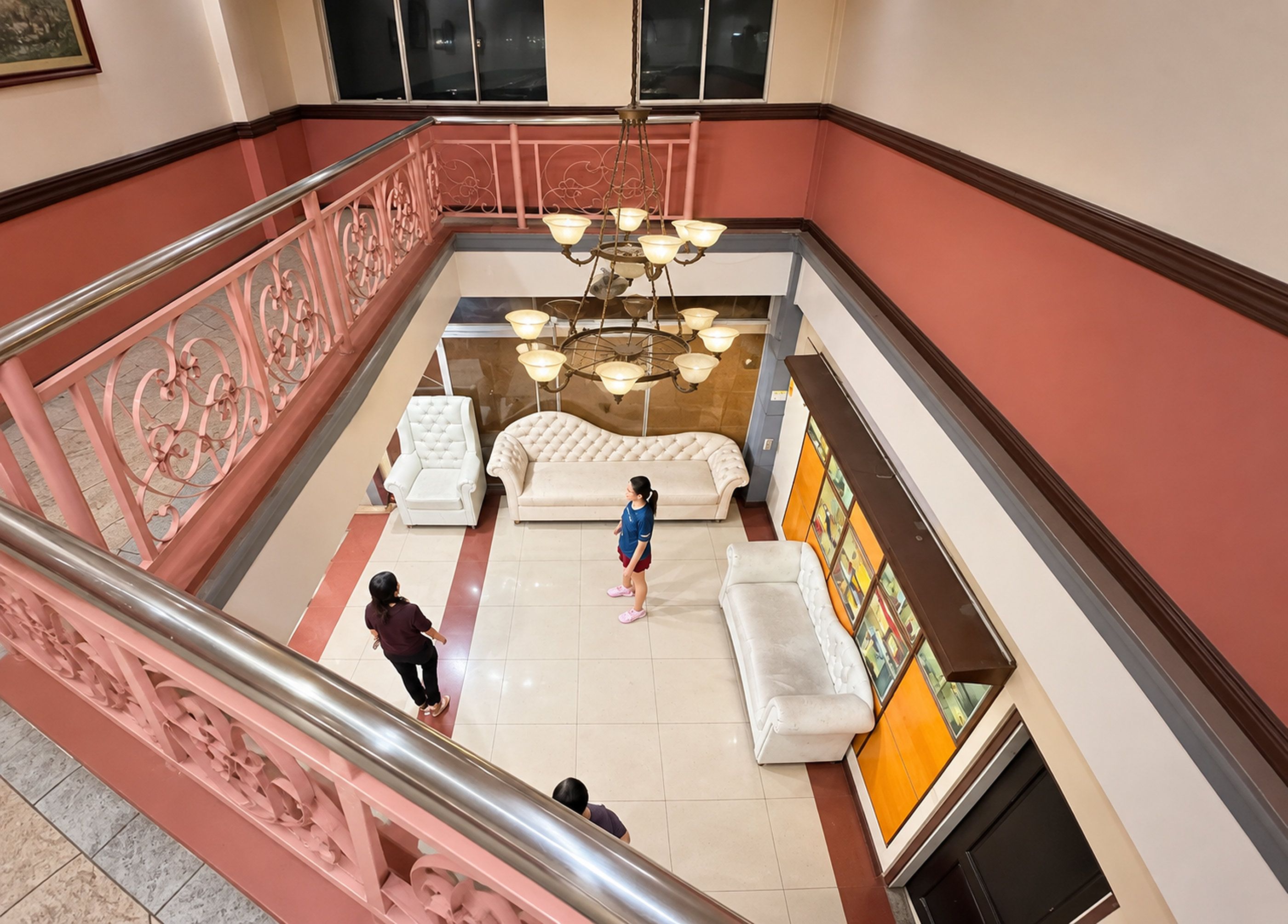 Un vestíbulo de hotel con una escalera, un candelabro y un área de descanso con sofás.