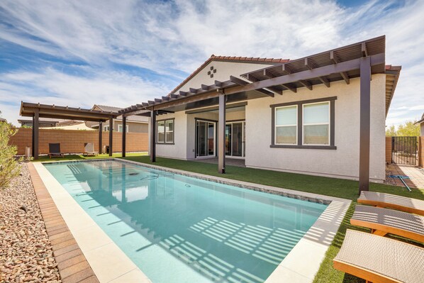 Uma casa moderna com piscina, varanda coberta e gramado bem cuidado.