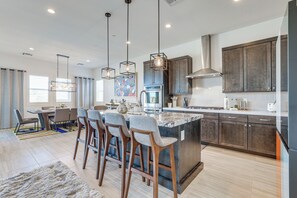 A modern kitchen with a central island, bar stools, pendant lighting, and dark cabinetry. - Peaceful & Modern Gem w/ Private Pool in Henderson (Henderson)