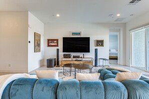 A modern living room with a large flat-screen TV, comfortable seating, and artwork on the walls. - Peaceful & Modern Gem w/ Private Pool in Henderson (Henderson)