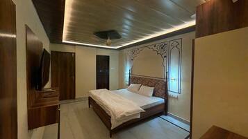 A bedroom with a wooden bed, a television, and a ceiling fan.