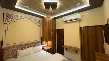 A bedroom with a bed, wooden wardrobe, and a wall-mounted shelf.