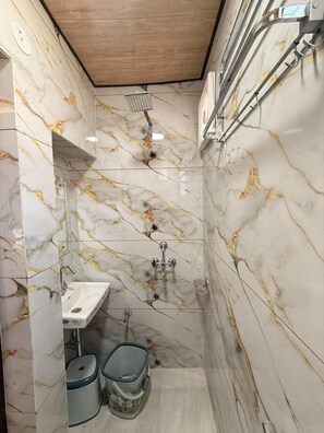 Un baño con ducha, lavamanos y paredes de mármol.