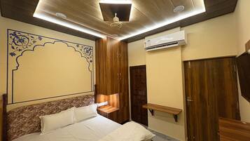 A bedroom with a bed, wooden wardrobe, an air conditioning unit, and a decorative wall design.