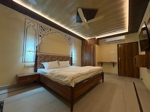 Un dormitorio con cama, mesitas de noche, ventilador de techo y armario.