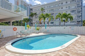 A swimming pool with a white fence, lounge chairs, and palm trees. - 1 Block to Sand! Ocean-View Retreat w/ Pool Access (Fort Lauderdale)
