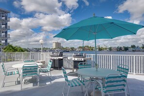 An outdoor patio with a grill, umbrella, and seating area overlooking a body of water and city skyline. - 1 Block to Sand! Ocean-View Retreat w/ Pool Access (Fort Lauderdale)