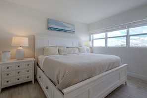 A bedroom with a large bed, two bedside tables, a nightstand, a window with a view, and a painting on the wall. - 1 Block to Sand! Ocean-View Retreat w/ Pool Access (Fort Lauderdale)