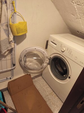 A laundry area with a washing machine, a drying rack, and a cardboard box. - Old Town of Celano (Celano)