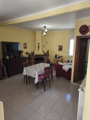A dining area with a table and chairs, a television, a fireplace, and a sofa. - Old Town of Celano (Celano)