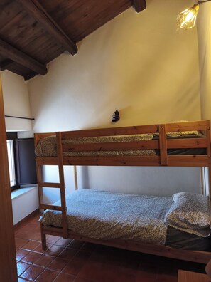 A bunk bed with a ladder, a hanging light fixture, and a window with a curtain. - Old Town of Celano (Celano)