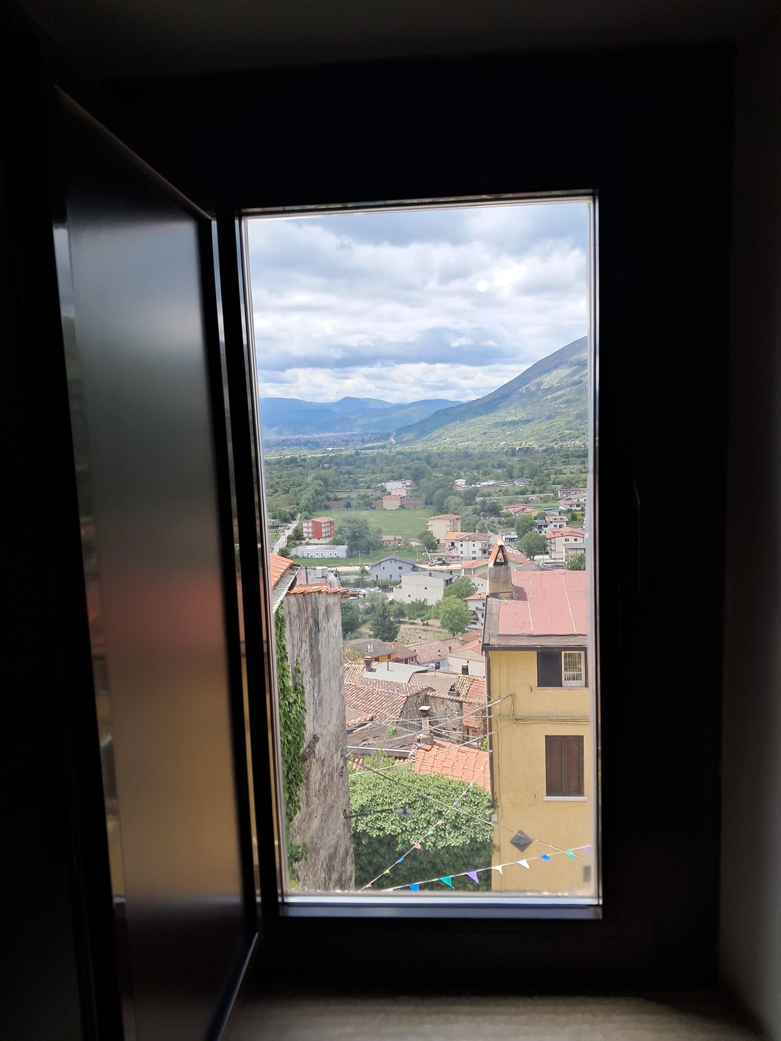 Ein Fenster mit Blick auf eine Stadt, Gebäude und Berge.