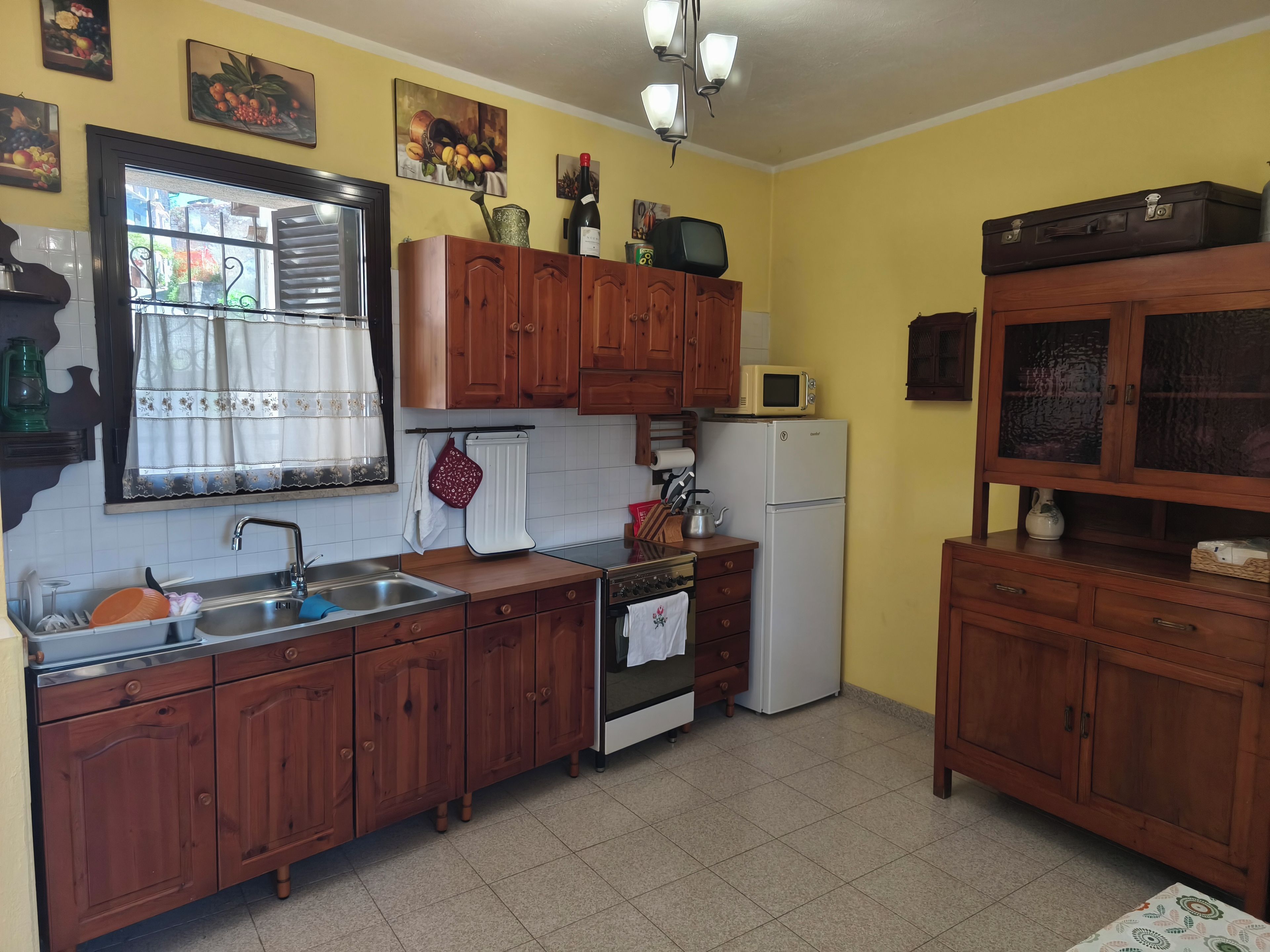 A kitchen with wooden cabinets, a refrigerator, a microwave, and a sink.