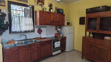 Eine Küche mit Holzausstattung, einem Kühlschrank, einer Mikrowelle und einem Spülbecken.