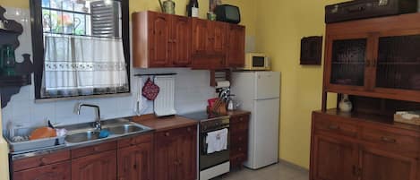 A kitchen with wooden cabinets, a refrigerator, a microwave, and a sink.