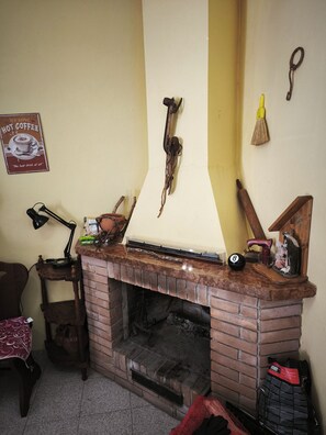 A brick fireplace with a mantel, a vintage sign, and a broom on the wall. - Old Town of Celano (Celano)