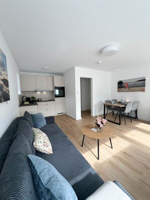 Ein stilvoller Wohnbereich mit einer Couch, einem Esstisch und einer Küchenzeile.