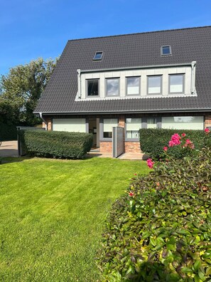 Ein zweistöckiges Haus mit einem grauen Ziegeldach, einer Haustür und einem kleinen Fenster im Obergeschoss.
