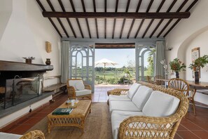 A cozy living room with a fireplace, wicker furniture, and a view of a green landscape. - La Certaldina, Luna Apartment (Certaldo)