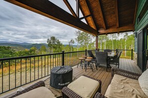 A covered outdoor seating area with wicker furniture, a table, and a black bag labeled 'Solo Stove.' - Luxe Couple's Cabin Retreat Outside Steamboat (Clark)