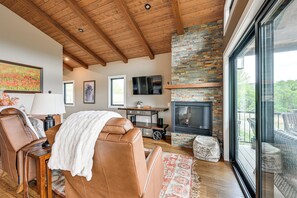 A modern living room with a fireplace, leather furniture, and large windows. - Luxe Couple's Cabin Retreat Outside Steamboat (Clark)