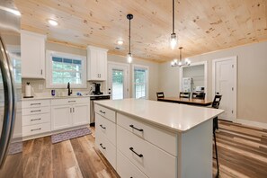 A modern kitchen with white cabinetry, a large island, and wooden flooring. - Home Near Kentucky Lake & Paris Landing! (Buchanan)