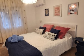 Ein Schlafzimmer mit einem Bett, Kissen, einem Nachttisch und einer Wand mit gerahmten Bildern.
