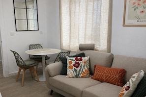 A living room with a sofa, a round table, and two chairs.